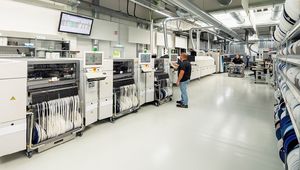 Ein Überblick über die Produktionshalle der FSM AG, in der moderne Maschinen und Produktionslinien zu sehen sind. Ein Mitarbeiter kontrolliert die Anlagen und sorgt für einen reibungslosen Ablauf.